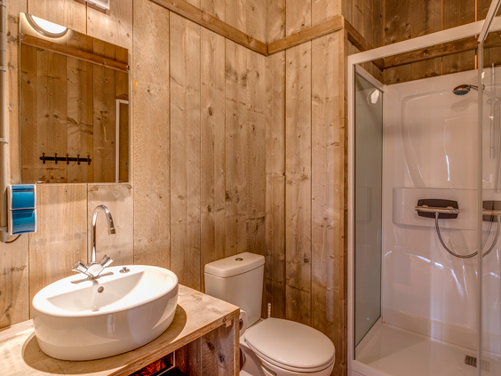 Een complete badkamer met houten wanden, een wastafel, toilet en douchecabine in een luxe glamping safaritent op Landal Sluftervallei.