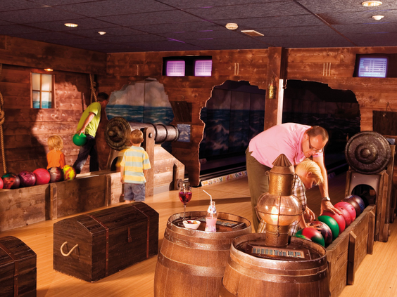 Kinderen en volwassenen zijn aan het bowlen op een bowlingbaan die is ingericht als een piratenschip, compleet met schatkisten en tonnen, op Landal Sluftervallei.
