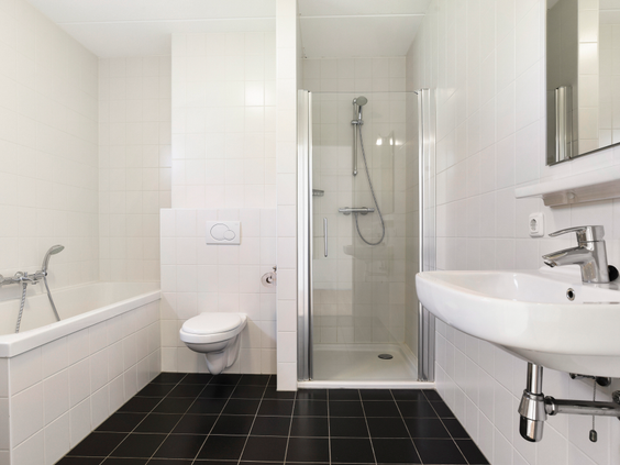 Moderne badkamer met een bad, aparte douche, wastafel en toilet in een vakantiewoning op Landal Sneekermeer.