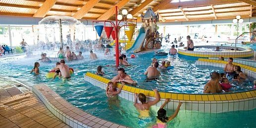 Veel mensen en kinderen hebben plezier in het drukke binnenzwembad met stroomversnelling op vakantiepark Landal Sonnenberg.