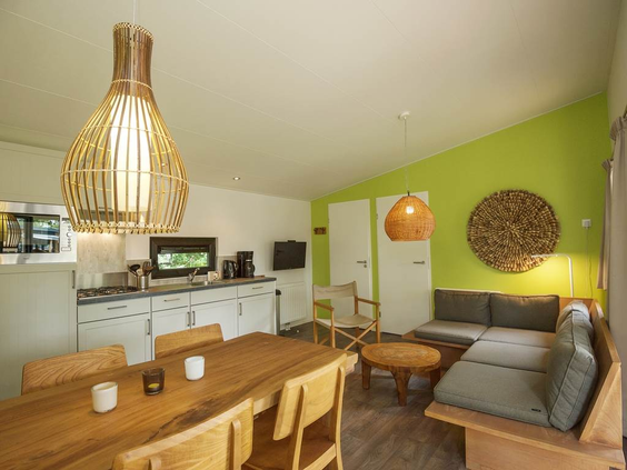 Het lichte en moderne interieur van een bungalow op Landal Sonnenberg, met een houten eettafel en een gezellige zithoek.