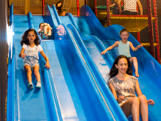Kinderen glijden met veel plezier van de brede blauwe familieglijbaan in het indoor speelparadijs op Landal Sonnenberg.