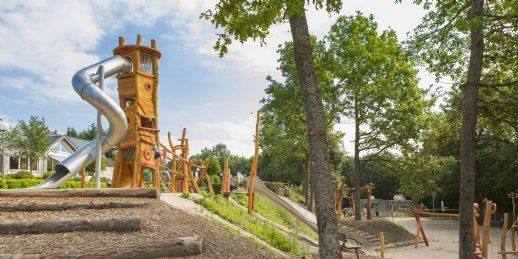 Een grote houten avonturenspeeltuin met diverse klimtoestellen en een glijbaan, gelegen in het groen op Landal Sonnenberg.