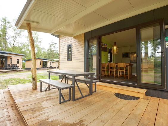 De veranda van een moderne bungalow op Landal Sonnenberg, met een houten terras en een picknicktafel om buiten te zitten.