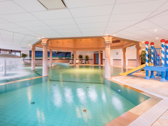 Het overdekte kinder- en kleuterbad met een kleine glijbaan en speelfiguren in het zwembad van Landal Stroombroek.