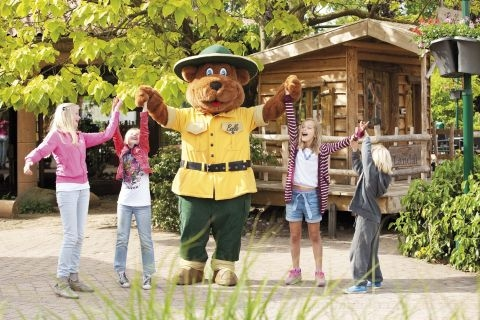 Kinderen dansen en zingen vrolijk samen met de mascotte Bollo de Beer bij de Kids Club van Landal Stroombroek.