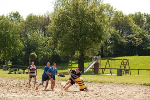 Jongeren spelen een potje beachvolleybal op het zandstrand bij de recreatieplas van Landal Stroombroek.