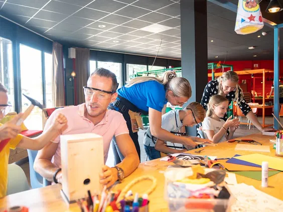 Kinderen en ouders zijn samen creatief aan het knutselen in de gezellige Bollo Club, onder begeleiding van het animatieteam van Landal 't Loo.