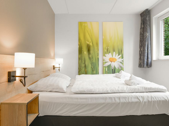 De moderne ouderslaapkamer in een bungalow op Landal 't Loo, met een comfortabel opgemaakt tweepersoonsbed en sfeervolle verlichting.