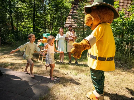 Enthousiaste kinderen begroeten en geven een high-five aan Bollo de Beer, de mascotte van Landal 't Loo.