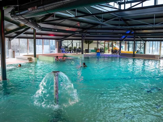 Het overdekte binnenzwembad van Landal 't Loo met een bruisend bubbelbad en zwemmende gasten in het helderblauwe water.