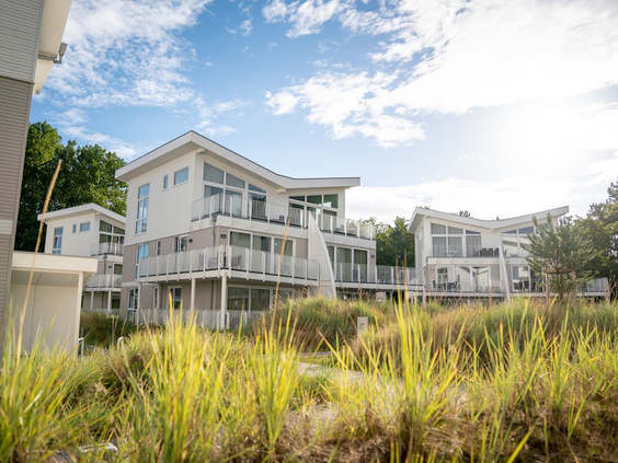 De moderne, witte vakantiehuizen van Landal Travemünde, gelegen in een natuurlijk duinlandschap vlak bij de Oostzeekust.