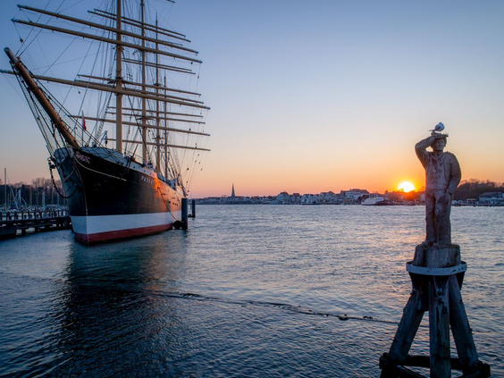Het historische zeilschip, de viermaster 'Passat', ligt in de haven van Travemünde tijdens een prachtige zonsondergang.