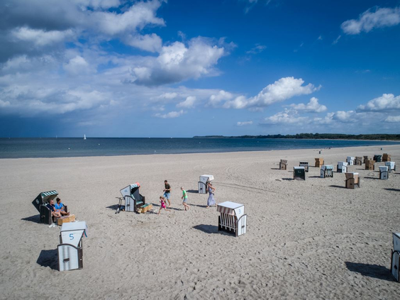 Het brede zandstrand van Travemünde aan de Oostzee, met diverse typisch Duitse rieten strandstoelen (Strandkorb).
