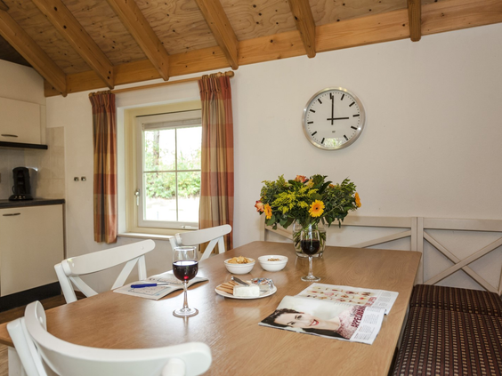 Een gezellige eethoek in een bungalow op Landal Twenhaarsveld, met een gedekte tafel en bloemen.