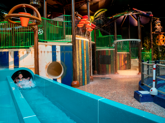 Kind komt van een blauwe waterglijbaan in de interactieve waterspeeltuin van het subtropisch zwemparadijs op vakantiepark Landal Vennenbos in Brabant.