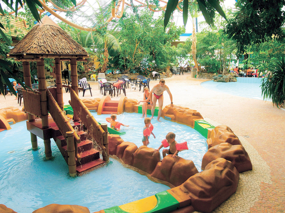 Kinderen spelen in het ondiepe kinder-doe-bad met een kleine glijbaan en speelelementen in het zwemparadijs van Landal Vennenbos in Brabant.