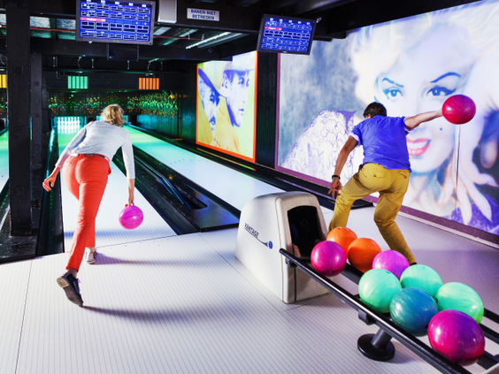 Een gezin is aan het bowlen op de moderne, sfeervolle bowlingbaan met kleurrijke ballen op het vakantiepark Landal Vennenbos.