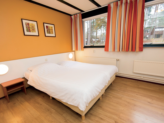 De netjes opgemaakte tweepersoonsslaapkamer in een comfortabele bungalow op het kindvriendelijke vakantiepark Landal Vennenbos in Noord-Brabant.