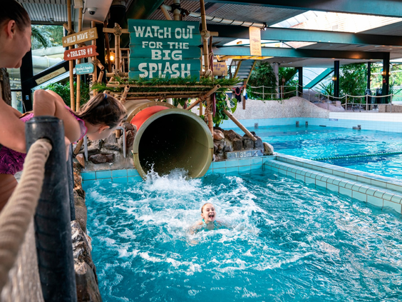 Kind maakt een 'Big Splash' aan het einde van de overdekte waterglijbaan in het zwembad van vakantiepark Landal Vennenbos in Noord-Brabant.