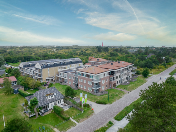 Luchtfoto van de moderne appartementencomplexen van Landal Vitamaris, omgeven door het groene landschap van Schiermonnikoog.