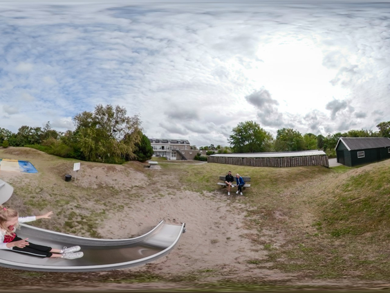 Panoramisch overzicht van de speelduin bij Landal Vitamaris waar kinderen van een brede glijbaan roetsjen in het zand.