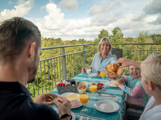 Een familie met kinderen en grootouders geniet van een zonnig ontbijt op het balkon van hun appartement bij Landal Vitamaris.