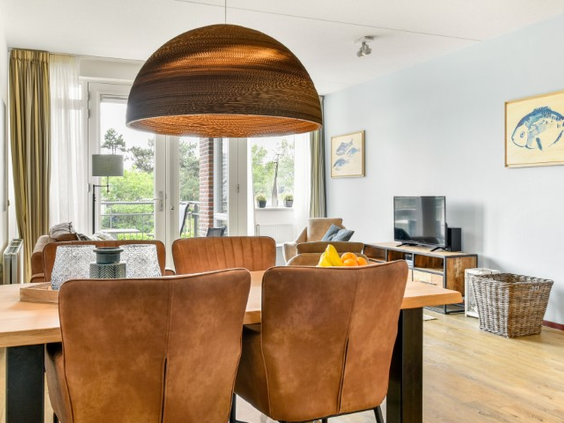 De sfeervolle eethoek in een appartement van Landal Vitamaris, met comfortabele leren stoelen rond een houten tafel.