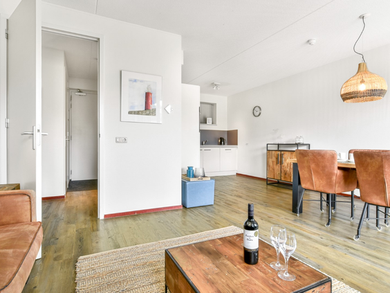 Overzicht van de stijlvol ingerichte woonkamer in een appartement op Landal Vitamaris, met een zithoek en eethoek.
