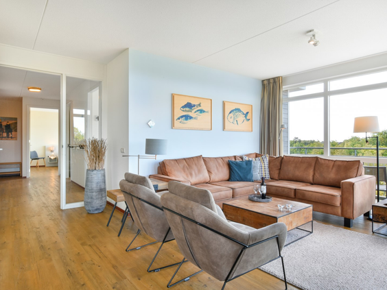 De comfortabele en ruime zithoek in een appartement van Landal Vitamaris, met een grote leren hoekbank en uitzicht naar buiten.