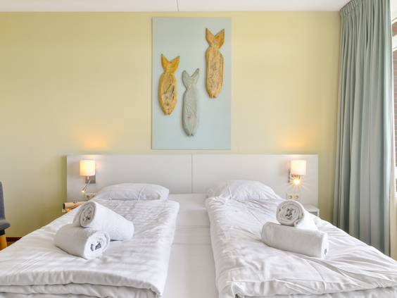 De tweede slaapkamer in een appartement van Landal Vitamaris, met opgemaakte bedden en vrolijke vis-decoratie aan de muur.