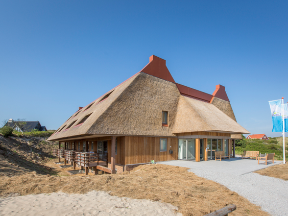 Het karakteristieke hoofdgebouw van Landal Vlieduyn met rieten dak, gelegen in de duinen van Vlieland.
