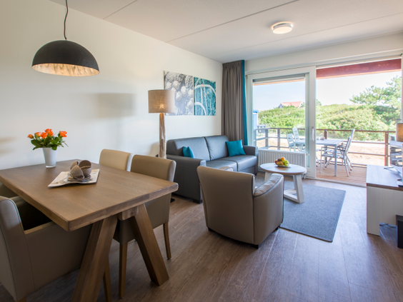 Sfeervol ingerichte woonkamer met zithoek en eettafel in een appartement van Landal Vlieduyn op Vlieland.