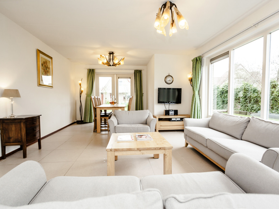 Lichte en ruime woonkamer van een vakantiehuis op Landal Vogelmient met een grote hoekbank, eethoek en uitzicht naar buiten.