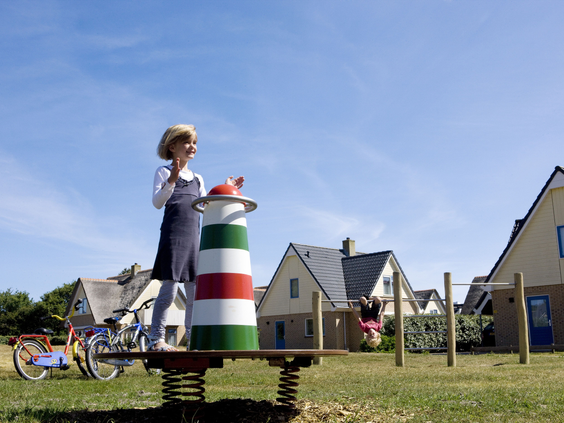 Kind speelt op een wipkip in de vorm van een vuurtoren in de speeltuin van vakantiepark Landal Vogelmient op Texel.