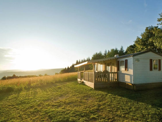Een moderne stacaravan met veranda op een ruime plek op de camping van Landal Warsberg, met een prachtig uitzicht over de heuvels.