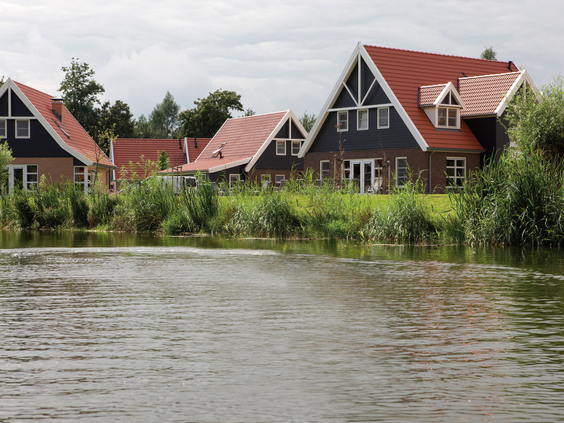 Karakteristieke vakantiehuizen met rode daken, direct gelegen aan het kabbelende water van Landal Waterparc Veluwemeer in Flevoland.