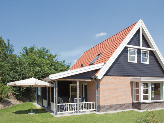 Een comfortabel vakantiehuis met een overdekte veranda en een grote parasol in de tuin, ideaal voor ontspanning op Landal Waterparc Veluwemeer.