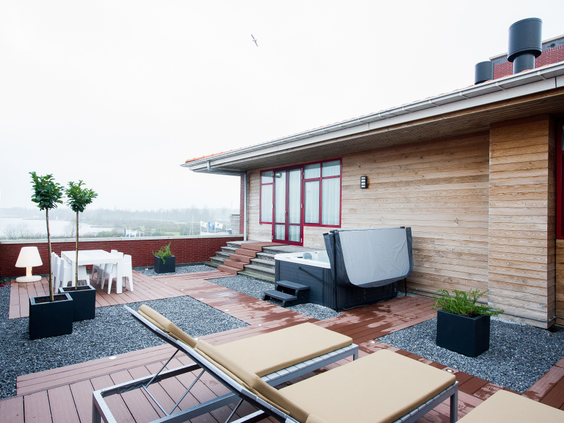 Het luxe dakterras van een penthouse-appartement met een privé-jacuzzi, ligbedden en uitzicht over het water op Landal Waterparc Veluwemeer.