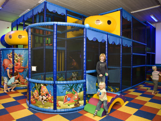 Kinderen spelen in het overdekte speelparadijs met klimrekken, glijbanen en een kleurrijke ballenbak op Landal Waterparc Veluwemeer.