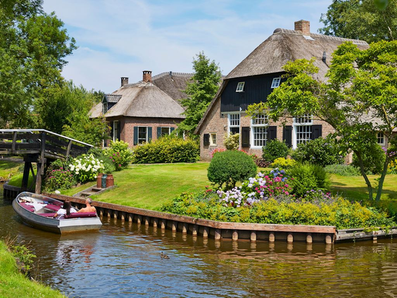 Een karakteristieke boerderij met rieten dak aan een gracht in het beroemde waterdorp Giethoorn, nabij Landal Waterresort Blocksyl.