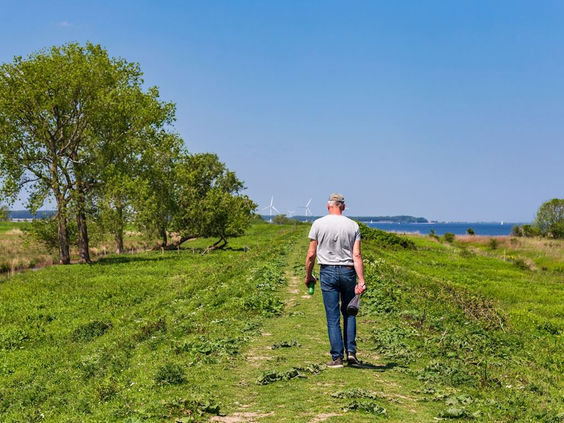 Een man wandelt over een groene dijk langs het water in de omgeving van Blocksyl met uitzicht over het meer.