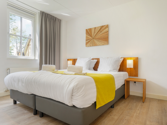 Stijlvolle en lichte slaapkamer met een opgemaakt tweepersoonsbed in een vakantiehuis op Landal Waufsberg.