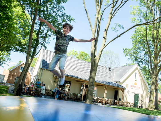 Een kind springt hoog in de lucht op de airtrampoline bij de horeca van vakantiepark Landal Waufsberg.