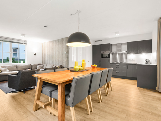 Modern interieur van de woonkamer en open keuken met een grote eettafel in een vakantiehuis op Landal Waufsberg.