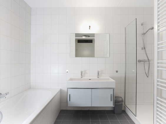 Een moderne, witte badkamer met ligbad, aparte douche en dubbele wastafel in een appartement op Landal West-Terschelling.