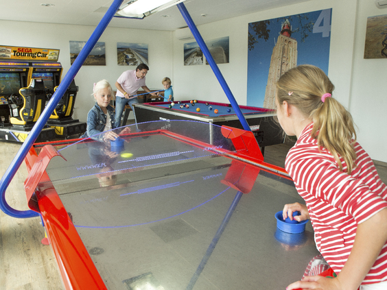 Kinderen spelen fanatiek een potje airhockey in de indoor speelruimte op Landal West-Terschelling.