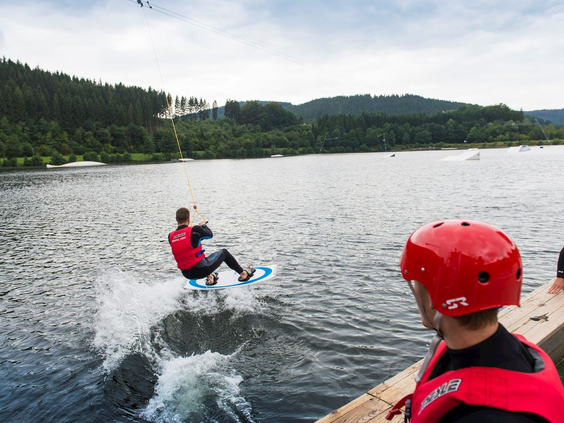 Een persoon is aan het wakeboarden op het nabijgelegen stuwmeer de Hillebachsee, een populaire watersportlocatie in de buurt van Winterberg.