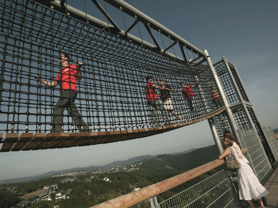 Kinderen klimmen en klauteren over een avontuurlijk nettenparcours op de Erlebnisbrücke Kappe, een attractie in Winterberg.
