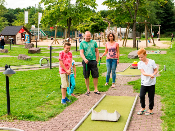 Een gezin speelt een gezellig potje midgetgolf op de avontuurlijke midgetgolfbaan van Landal Wirfttal.